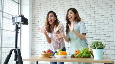 Asyalı vlogger canlı yayında sağlıklı beslenme tarzı hakkında yorum yapıyor. İki genç bayan arkadaş blogcu mutlu bir yaşam tarzı sunuyor. Sebze, meyve, vejetaryen ürünleri nasıl yenir. İki kadın sosyal medya vlog 'undan bahsediyor