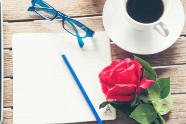 Üst kat ofis masası akıllı tablet kağıt, kahve fincanı gülleri ahşap masada fotokopi alanı ile. Masaüstü not defteri ofisi boş beyaz kağıt kalem kahve fincanı çalışma alanı ahşap zeminini göstermek için