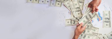 Banner Hand 'in elinde borç para banknotları var. Afiş Adam 'ın elleri, 100 dolarlık takas paralarını fotokopi alanlarıyla gösteriyor. İş adamının para tasarrufu. Rüşvet konsepti.