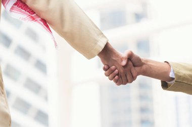 Arab Businessman shaking hands together. Teamwork business partner wear Muslim dress Shake Hands with Partnership Concept. Success UAE diversity people trust make commitment by handshake