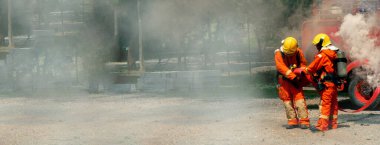 Firefighter Rescue training in fire fighting extinguisher. Firefighter fighting with flame using fire hose chemical water foam spray engine. Fireman wear hard hat, safety suit uniform for protection