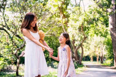 Yeşil bahçe parkında anne kız birlikte baloncuk oynuyor. Mutlu bir aile iki insanın mutlu bir gülüşü olur en iyi arkadaşlar. Asyalı şirin çocukluk oyun balonu dışarıda