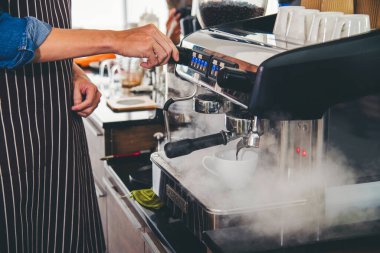 Close up hands coffee barista man make hot cup espresso shot from coffee machine. Cappuccino with milk in italian coffee shop cafe. Close up hands of barista use machine make black drinking hot cup