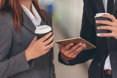 Genç Asyalı iş adamları gülümsüyor. İşe gitmeden önce bir fincan kahve içiyorlar. Çift aşık modern şehirde birlikte kahve içmekten hoşlanır. Ofiste elinde kahve tutan iş adamları.