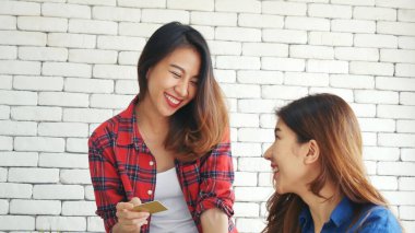 İki arkadaş internetten alışveriş yapıyor. İnternet sitesinde bilgisayardan alışveriş yapıyor. Gülümseyen yüzlü, mutlu. İnternetten bilgisayar alışverişi yapan mutlu Asyalı kadınlar, yeni konsept ödeme