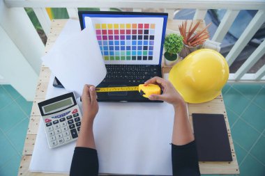 Ofis masasında çalışan kadın mühendis elleri. Mimar planları çizen kadın mühendisler evrak masası malzemeleri yazıyorlar. Mühendislik ölçü yapısını hesapladı.