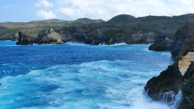 Turkuaz okyanus suyu beyaz dalga açık mavi deniz. Kuş bakışı canavar dalgası kayaya çarpıyor. Yazın açık deniz sahillerinde tropik deniz plajı. Okyanus adası güzel dramatik manzara.