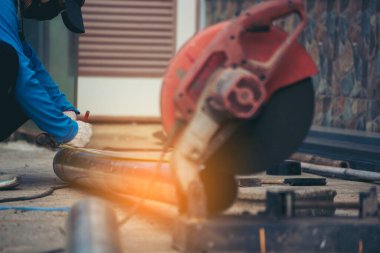 İnşaat işçisi elleri kaynak makineleri ile metal kıvılcımlar saçıyor. Erkek elleri koruyucu eldiven giyer. Alev metali, ateş demiri atölyesini keser. Çilingir kaynak makinesi kullanarak metal işlemini kesti