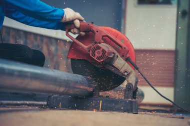 Erkek elleri koruyucu eldiven giyer. Alev metali, ateş demiri atölyesini keser. Çilingir kaynak makinesi kullanmış. Metal işlemleri kesmiş. Kaynak makinesi kullanan inşaat işçisi elleri demir gibi kıvılcım saçıyor.