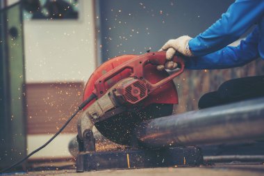 İnşaat işçisi elleri kaynak makineleri ile metal kıvılcımlar saçıyor. Erkek elleri koruyucu eldiven giyer. Alev metali, ateş demiri atölyesini keser. Çilingir kaynak makinesi kullanarak metal işlemini kesti