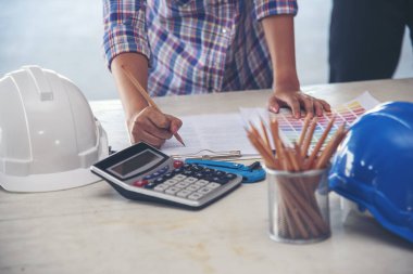 Ofis masasında çalışan kadın mühendis elleri. Mimar planları çizen kadın mühendisler evrak masası malzemeleri yazıyorlar. Mühendislik ölçü yapısını hesapladı.