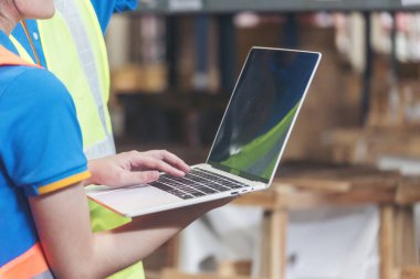 Depo yönetimi bilgisayar dizüstü bilgisayarı kullanarak stok envanterini kontrol ediyor. Asyalı erkek kadın işçi yazılım bilgisayar tipi klavye ürünleri rafı kullanıyor. Takım çalışması lojistik personeli stok envanterini sayıyor