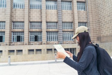 Asyalı genç bayan gezgin müzede harita broşürlerine bakıyor. Kadın yolcu, uçak turistlerinin bagajlarıyla seyahat ediyor. Tatildeki kadınların turizmi kutlu olsun. Rahatla kadınlar eski şehirde yürüyor..