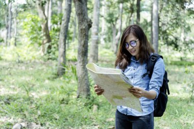 Dışarıdaki kadınlar yeşil doğa parkında harita arayan Asyalı genç kadın gezginler. Tatilde elinde broşür tutan bayan turist. Mutlu turizm gezileri. Kadınlar parka doğru yürür.