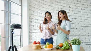İki Asyalı vlogcu birlikte sağlıklı bir yaşam tarzı gözden geçiriyorlar. İki Genç Kadın Arkadaş blogcusu Mutlu Yaşam Biçimi Canlı Yayın. İki kadın sosyal medyadan konuşuyor, merhaba de.