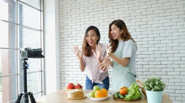 İki Asyalı vlogcu birlikte sağlıklı bir yaşam tarzı gözden geçiriyorlar. İki Genç Kadın Arkadaş blogcusu Mutlu Yaşam Biçimi Canlı Yayın. İki kadın sosyal medyadan konuşuyor, merhaba de.
