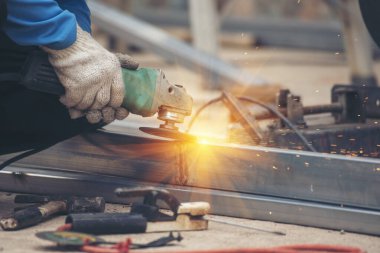 Erkek elleri koruyucu eldiven giyer. Alev metali, ateş demiri atölyesini keser. Çilingir kaynak makinesi kullanmış. Metal işlemleri kesmiş. Kaynak makinesi kullanan inşaat işçisi elleri demir gibi kıvılcım saçıyor.