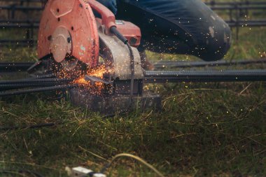 İnşaat işçisi elleri kaynak makineleri ile metal kıvılcımlar saçıyor. Erkek elleri koruyucu eldiven giyer. Alev metali, ateş demiri atölyesini keser. Çilingir kaynak makinesi kullanarak metal işlemini kesti