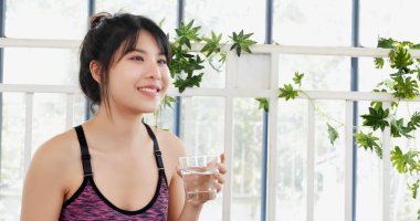 Neşeli güzel bayan bir bardak su gülümseyen surat iç. Su içen kadın elinde soğuk maden suyu, soğuk içecek. Asyalı kadınlar güler, sağlık hizmetleri yaşam tarzını görmezden gelirler.