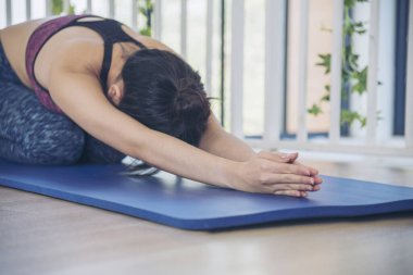 Kadınlar yoga meditasyonu geriliyor, kollar evde meditasyon yapıyor yerde. Yoga yapan genç kadınların mutluluğu Balasana çocuk pozu. Spor giyim sektöründeki sağIıklı kadın rahatlama, rahatlama ve sağlık hizmetlerinde meditasyon yapıyor.