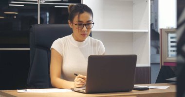 İş kadını elleri, ofis masasındaki defter toplantısına dizüstü bilgisayarla yazı yazar. Asyalı Kadın Eller ofis kâğıdına yazı yazıyor. Dizüstü bilgisayardan takvim kullanıyor. Kalem tutan kadın iş planı.