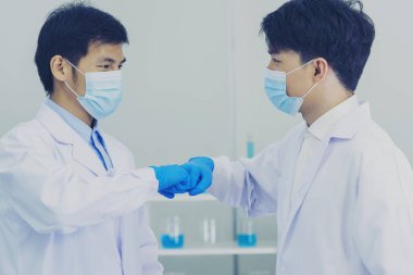 İki Asyalı bilim adamı yumruk tokuşturup takım arkadaşı oluyor. Ekip Adamları bilim kimyası araştırması laboratuvarda başarıyla çalışıyor. El farmasötik bilimi kurumsal ortaklığını kapatın.