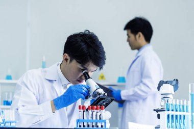 Bilim adamı bilim laboratuarındaki mikroskop araştırmalarını inceliyor. Asyalı bilim adamı laboratuvar kimya laboratuvarlarını arıyor. Covid-19 Coronavirus biyokimya araştırma deneyi aşı konsepti