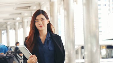 İş kadını kolları çaprazlanmış modern şehir arka planındaki kameraya gülümsüyor. Mutlu İş Adamları ayakta durup gülümseyin. Mutlu yönetici genç Asyalı kadın lider