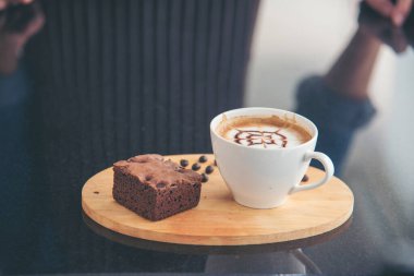 Sütlü, ahşap masadaki Latte sanat kahve fincanı. Espresso shot 'la sütlü kahve fincanı yapılır. İtalyan kafeteryasında sütlü kapuçino. Kafeteryada fotokopi alanı olan kahverengi kahve içeceği.
