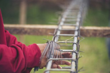 Kerpeten kullanan inşaat işçisi elleri demir tel kullanıyor. Açık hava işçisi, kerpeten kullanıyor, inşaat işlerinde çalışıyor. Erkekler elleri büküyor çelik telleri kesiyor beton işçiliğini destekliyor.