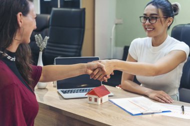 İş kadını, emlakçı müşteriyle el sıkışıyor ve kontrat imzalıyor. Takım çeşitliliği kadın satış temsilcisi ofis masası. Sigorta ipotekli satış belgesinde kadın el sıkışma işareti