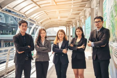 Portrait Group of businesspeople arms crossed smiling look at camera in modern city background. Happy Businessman, businesswoman teams partnership. Business people teams positive teamwork standing.
