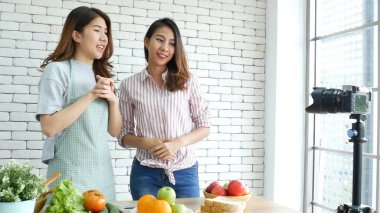 Asyalı vlogger canlı yayında sağlıklı beslenme tarzı hakkında yorum yapıyor. İki genç bayan arkadaş blogcu mutlu bir yaşam tarzı sunuyor. Sebze, meyve, vejetaryen ürünleri nasıl yenir. İki kadın sosyal medya vlog 'undan bahsediyor