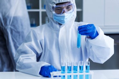 Scientist man holding sample blood test tube in science laboratory. Doctor clinic healthcare technician lab testing blood sample diagnosis. Asian man scientist working in hiv testing medical lab.