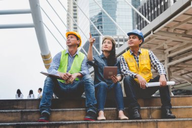 Müteahhit inşaat mühendisi toplantısı inşaat alanındaki mimar masasında konuşuyor. İş adamı mühendis müdürü ustabaşı ekip kurucusuyla görüşüyor. Plan planına bak.