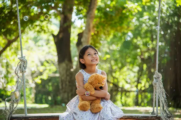 Yeşil Park 'ta oyuncak ayıya sarılırken mutlu çocuk. Oyuncak ayı, küçük çocuklar için en iyi arkadaş tatlı kız. Otizm mutlu bir şekilde oyun bahçesinde birlikte oynayarak mutlu bir aile sevgisi ve sıcacık kucaklaşmayı hisseder.