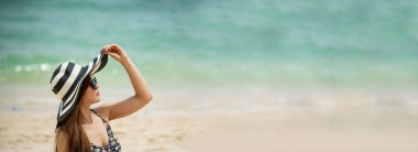 Yazlık kumsalda duran afiş hatunları hasır şapka giyerler. Tropik yaz plajlarında çıplak ayaklı neşeli Asyalı kadın. Sahilde yürüyen bir kadın. Özgürlüğü fotokopi aletiyle rahatlat.