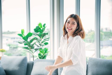 Mutlu Asyalı dansçı kadın kulaklık takıyor akıllı telefondan müzik dinliyor evdeki oturma odasında mutlu dans ediyor. Müzik terapisti, rahatlatıcı kadın. Neşeli sağIık, kadınlar iyi bir şekilde dans ediyor.