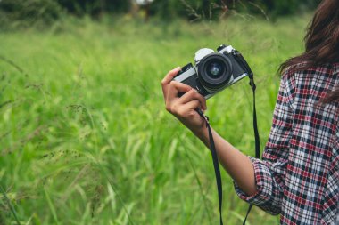 Eller yukarı, Asyalı kadınlar DSR dijital kamera klasik film tarzına bakıyor. Fotoğraf çekin. Profesyonel bayan fotoğrafçı dışarıdaki resme bakar. Yeşil doğa parkında fotoğraf çeken genç bir kadın.