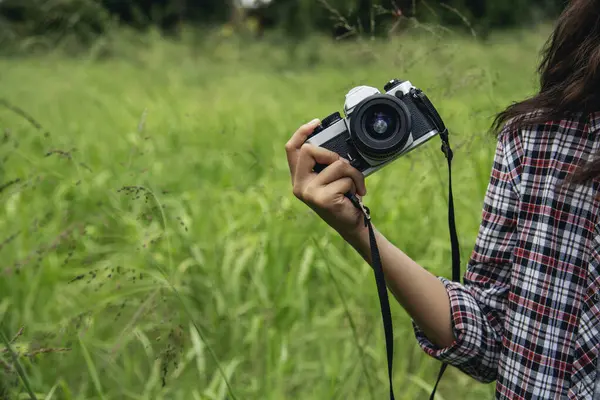 Eller yukarı, Asyalı kadınlar DSR dijital kamera klasik film tarzına bakıyor. Fotoğraf çekin. Profesyonel bayan fotoğrafçı dışarıdaki resme bakar. Yeşil doğa parkında fotoğraf çeken genç bir kadın.
