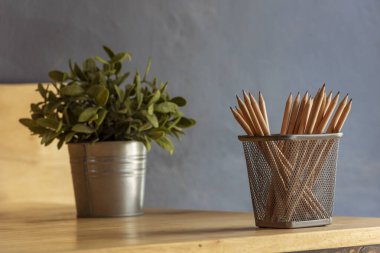 Ahşap masaya kalem keskinliğinde ofis dekorasyonu dikin. Yeşil dekore edilmiş ofis masası. Ahşap ofis masasındaki yeşil bitki vazosu kalem kutusu, çiçek saksısı ev ofisinin dekorasyon masası.