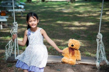 Yeşil Park 'ta oyuncak ayıya sarılırken mutlu çocuk. Oyuncak ayı, küçük çocuklar için en iyi arkadaş tatlı kız. Otizm mutlu bir şekilde oyun bahçesinde birlikte oynayarak mutlu bir aile sevgisi ve sıcacık kucaklaşmayı hisseder.