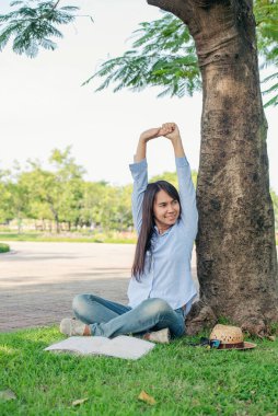Kolunu uzatan kadın yanlış pozisyonda oturarak ofis masasında oturuyor. Genç Asyalı kadının arka tarafı iş stresinden yorgun sırt ağrısı ofis sendromu. Evden kadın işi. Yeni normal kavram.