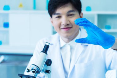 Bilim adamı bilim laboratuarındaki mikroskop araştırmalarını inceliyor. Asyalı bilim adamı mikrobiyoloji mikroskop laboratuvar ekipmanları kimya laboratuvarına bakıyor. Biyokimya araştırma aşısı konsepti