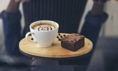 Sütlü, ahşap masadaki Latte sanat kahve fincanı. Espresso shot 'la sütlü kahve fincanı yapılır. İtalyan kafeteryasında sütlü kapuçino. Kafeteryada fotokopi alanı olan kahverengi kahve içeceği.