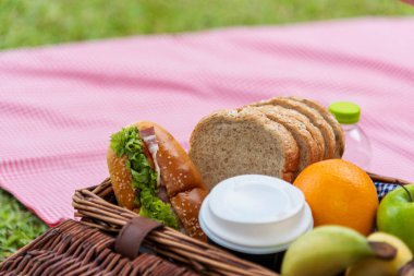 Piknik sepeti ekmeği taze meyve kahve fincanı portakal suyu ahşap hasır kutuda kırmızı battaniye üzerinde. Yeşil Park 'ta açık hava yaşam tarzında buğday fırını meyve ve içecekler. Kahvaltı, sağlıklı aperatif kutusu..