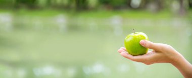 Banner genç Asyalı kadın yeşil Apple Sağlıklı 'yı ısırıyor. Organik elma meyvesi tutan kız sporu sağlıklı bir yaşam tarzı. Banner, kadınların ellerini yeşil elmayla kapat. Fotokopi alanı ile diyet yapan kadınlar