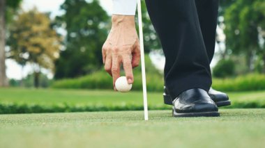 Golf topu antrenmanı yapan iş adamı golf kulübünün açık yeşil sahasında spor eğitimi kursuyla golf sahasında vuruş yaptı. Golf hobileri olan siyah takım elbiseli iş adamları.