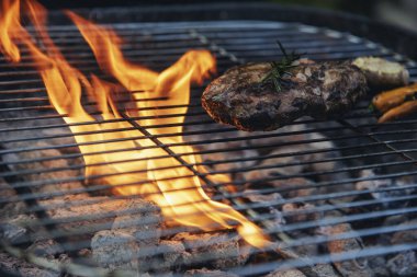 Barbekü ızgara et çubuğu ateşte, dışarıda da sıcak kömür var. Parti için domuz pastırmalı sosisli ızgara piknik. Izgara domuz eti ateşte yanıyor.