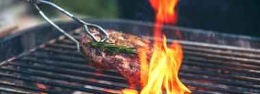 Banner BBQ Barbekü ızgara et çubuğu ateşte kızartılıyor, dışarıda kömür pişiriliyor. Banner Beef ızgara piknik pirzolası domuz pastırması Amerikan mutfağı. Izgara domuz eti, bbq raf alevi ve fotokopi alanı